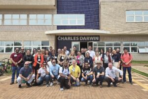A imagem mostra o grupo que realizou a visita técnica no Biopark em frente ou prédio com o letreiro escrito "Charles Darwin". Fim da descrição.